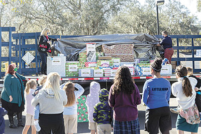 Ferguson HVAC Tampa Inside Sales Supervisor Susan Cardinal (on truck left) and Tampa Branch Manager Amy McPherson (on truck right) reveal the gifts as Recover Tampa Bay Initiative Executive Director Kate McPherson (far left) and Hope Children’s Home staff and residents look on.